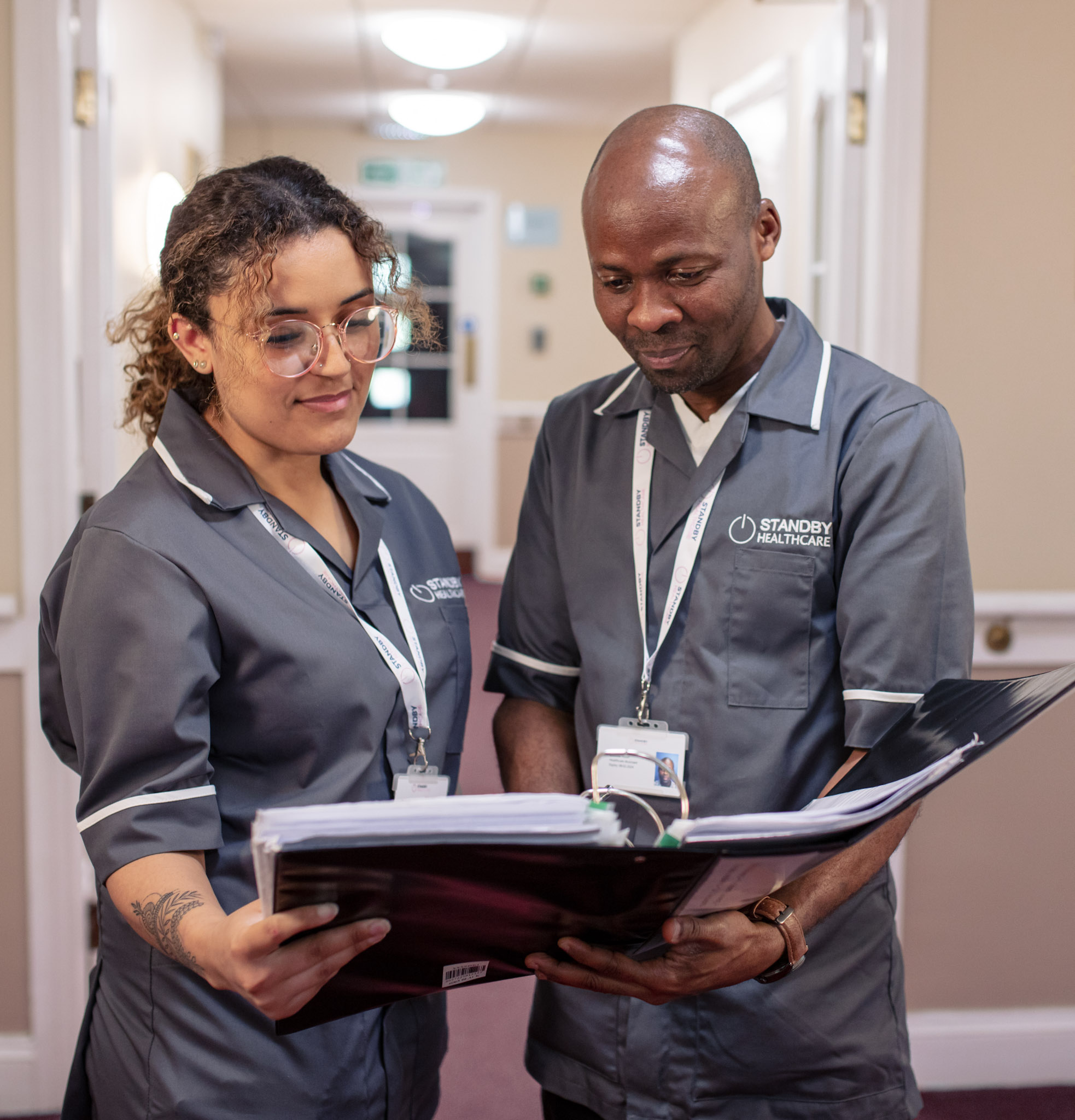 Two care staff holding and reading a folder together