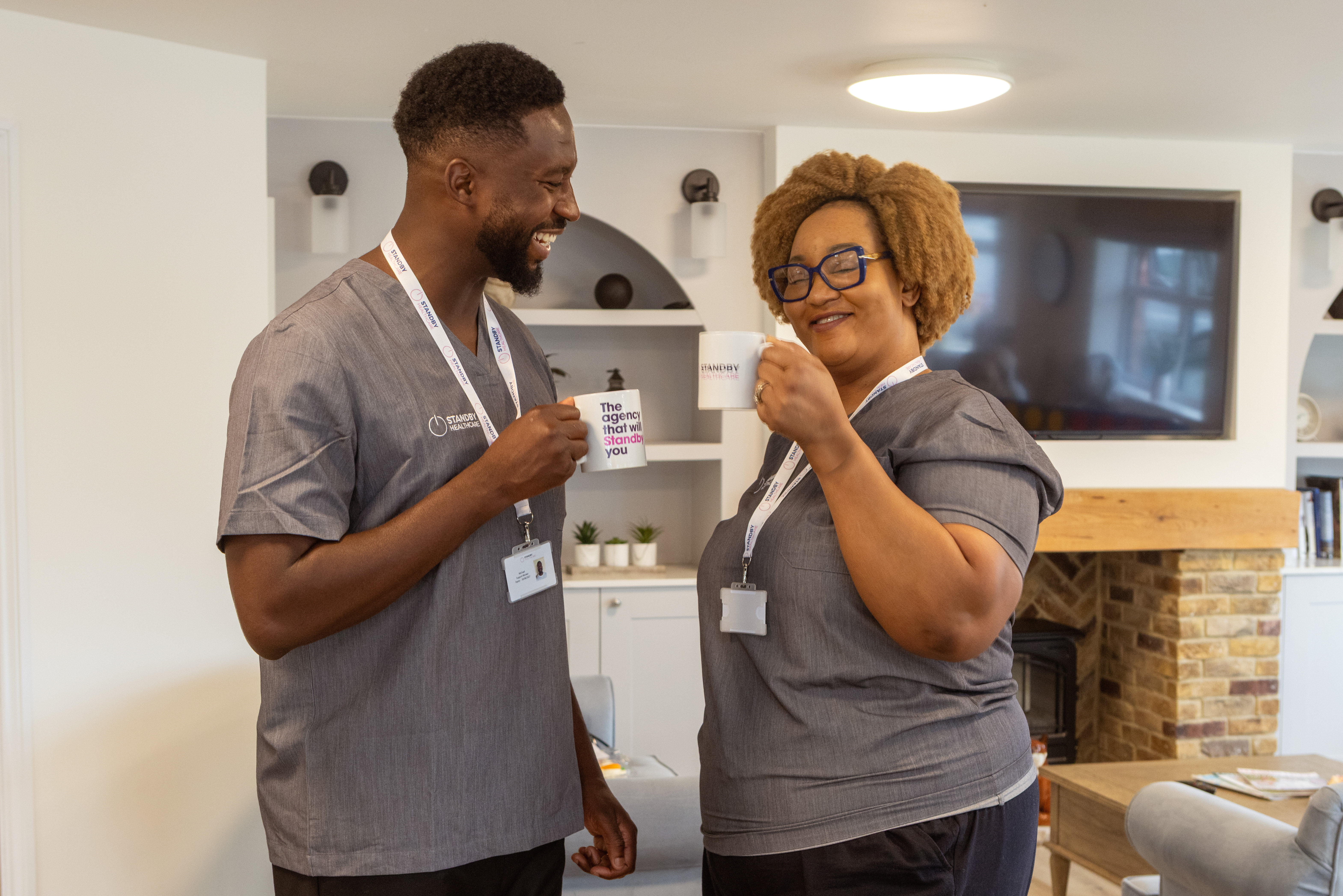 A male and female care staff member stood doing a 'cheers' with a Standby Healthcare cups