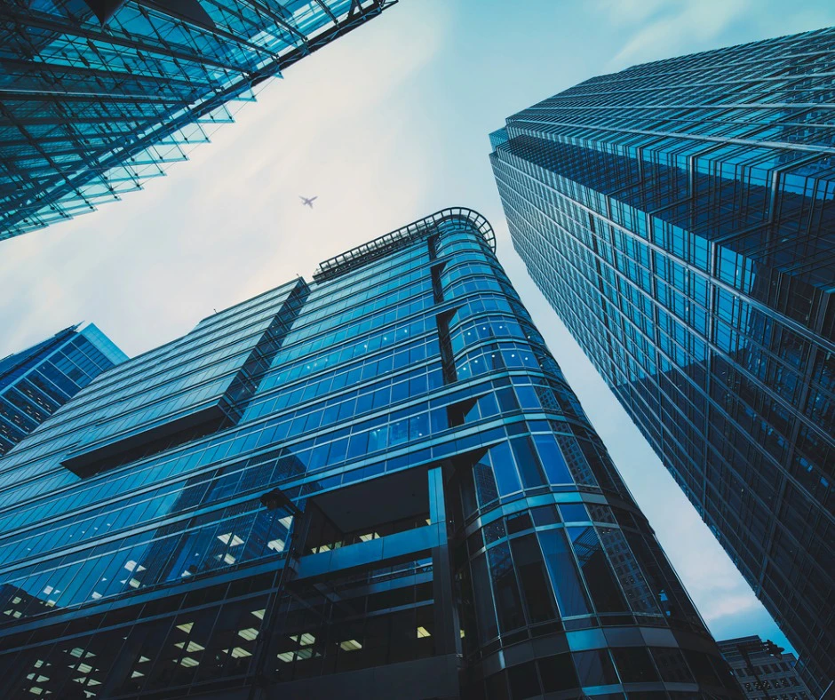 City scape looking up at jet between office towers