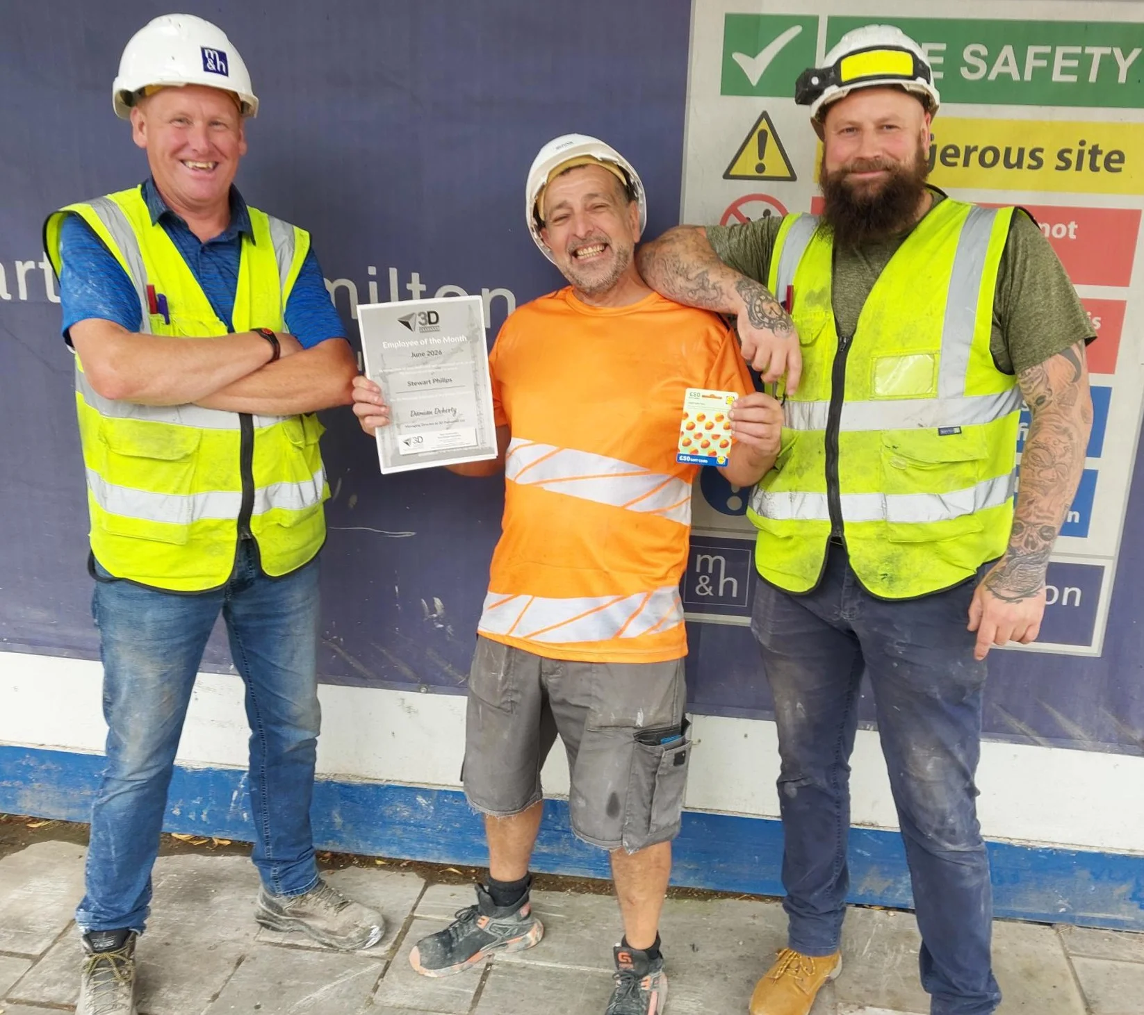 Stewart displays his award alongside David (left) and John (right) at the Belfast site