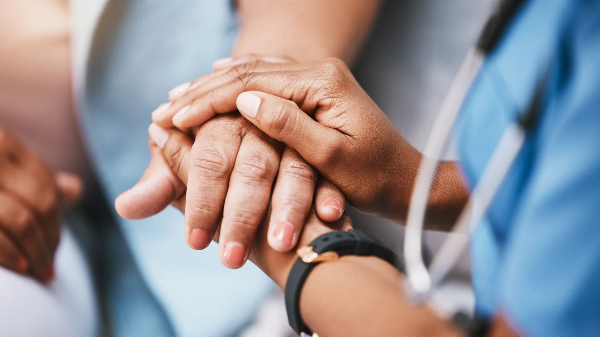 Close-up of a nurse holding a patient’s hand in a hospital setting, showing compassionate healthcare support and medical care.