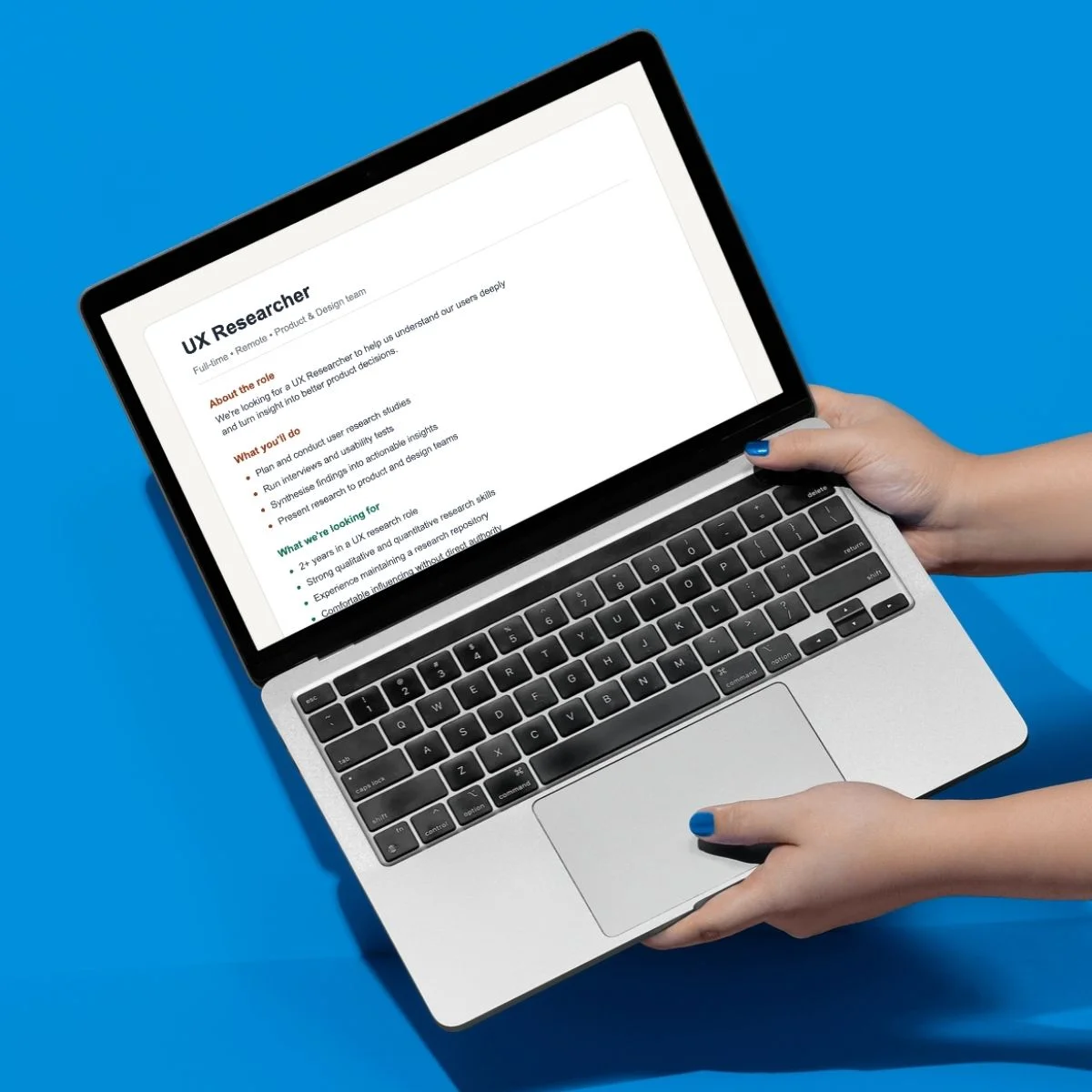 Laptop on a bright blue background with an example UX Research job description on the screen.