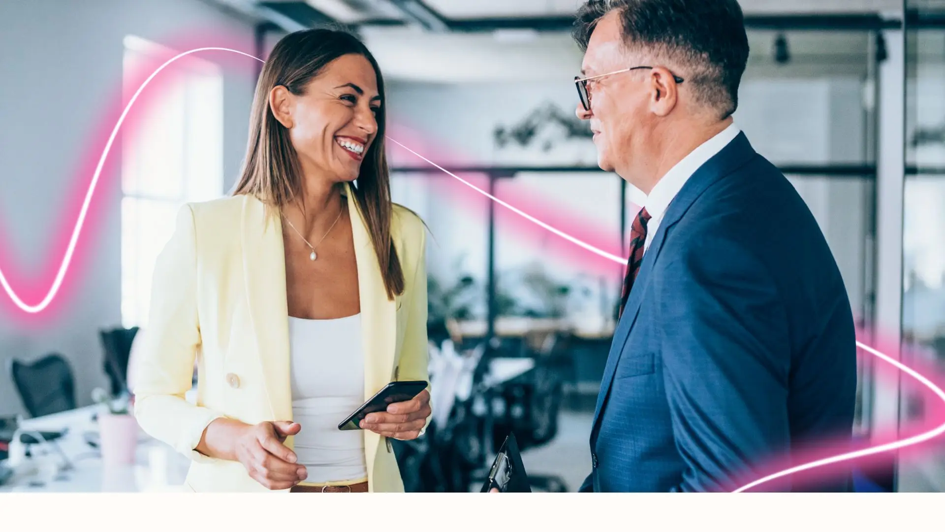 Smiling woman and man in business attire having a conversation in a modern office with pink neon light trails in the background.