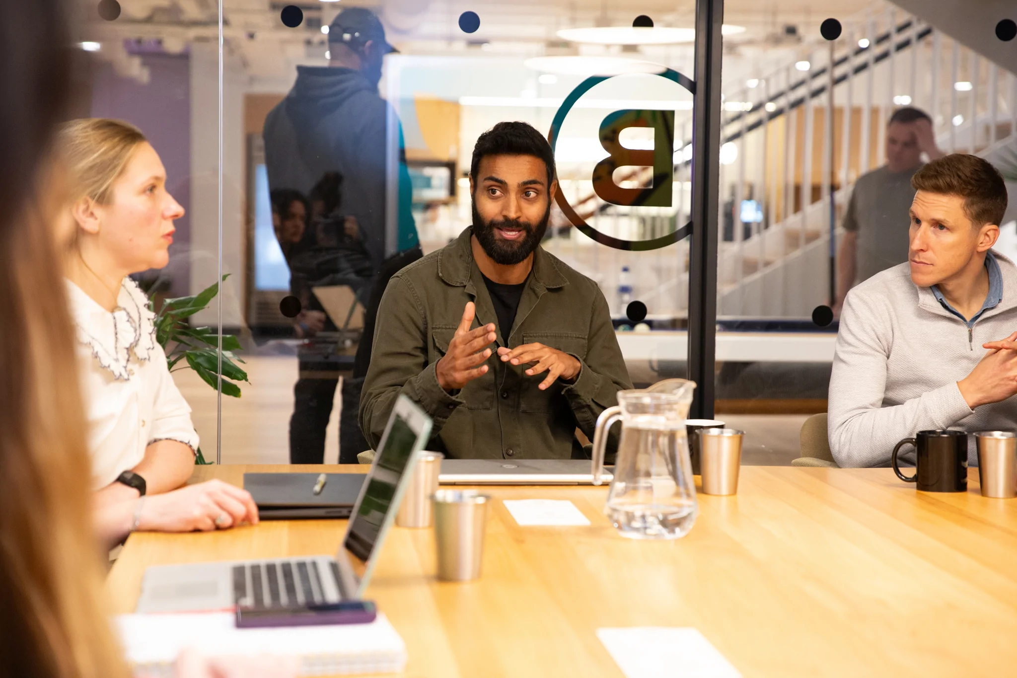 Two men and one woman sit round a table having a meeting