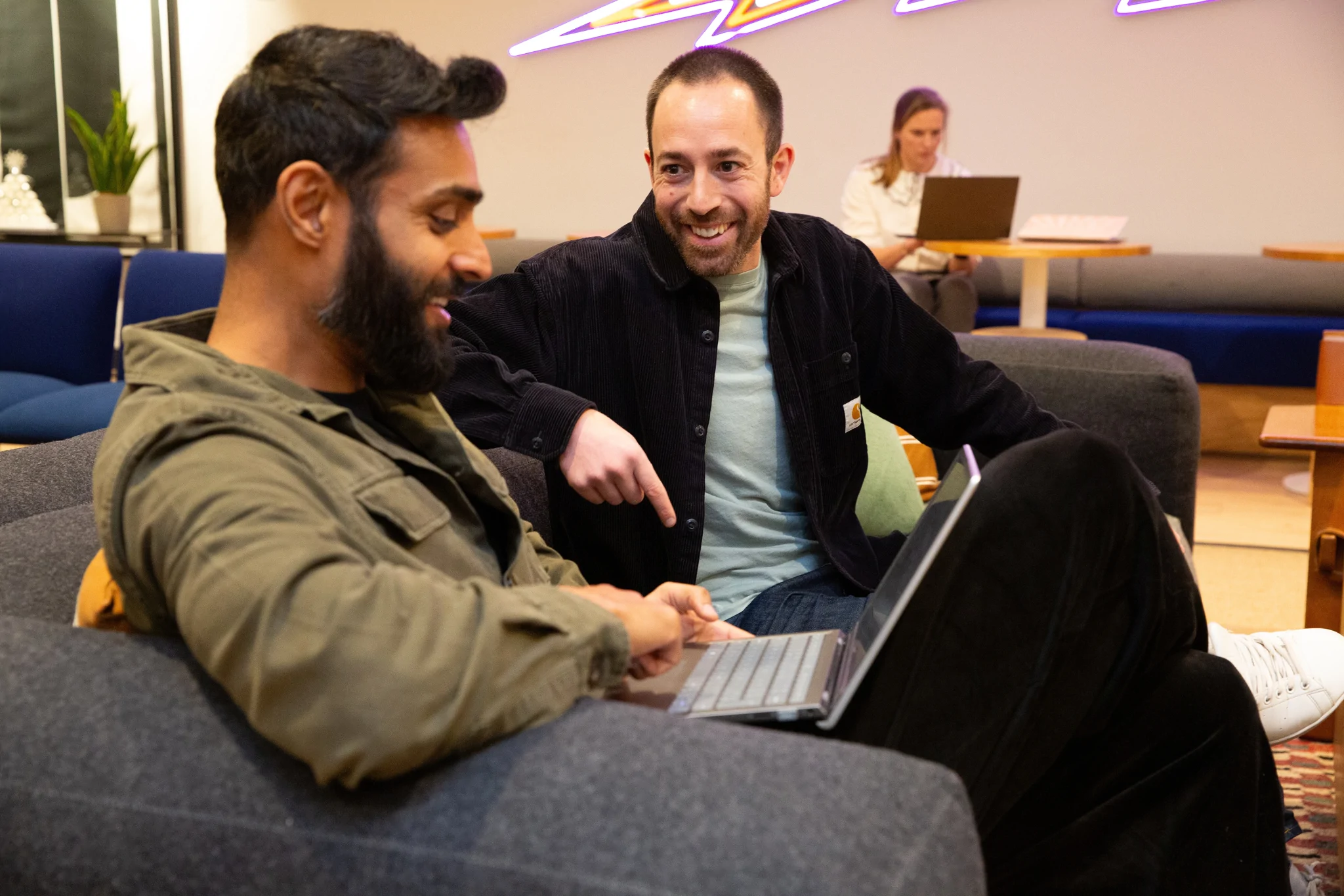 Two men sitting and talking over a laptop