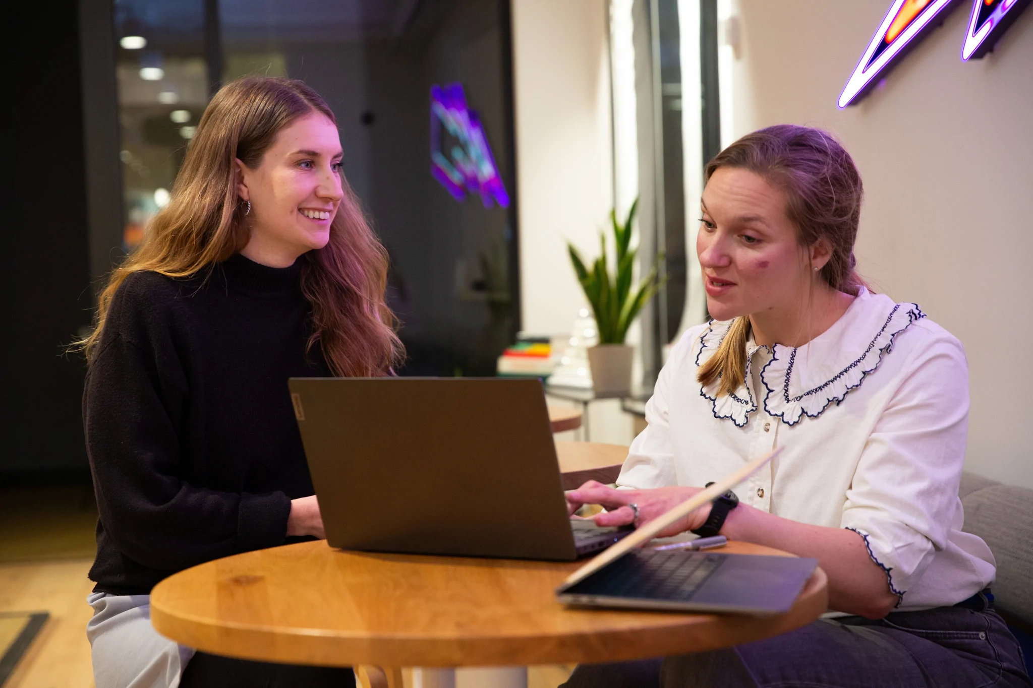 Two women working together at a table with a laptop