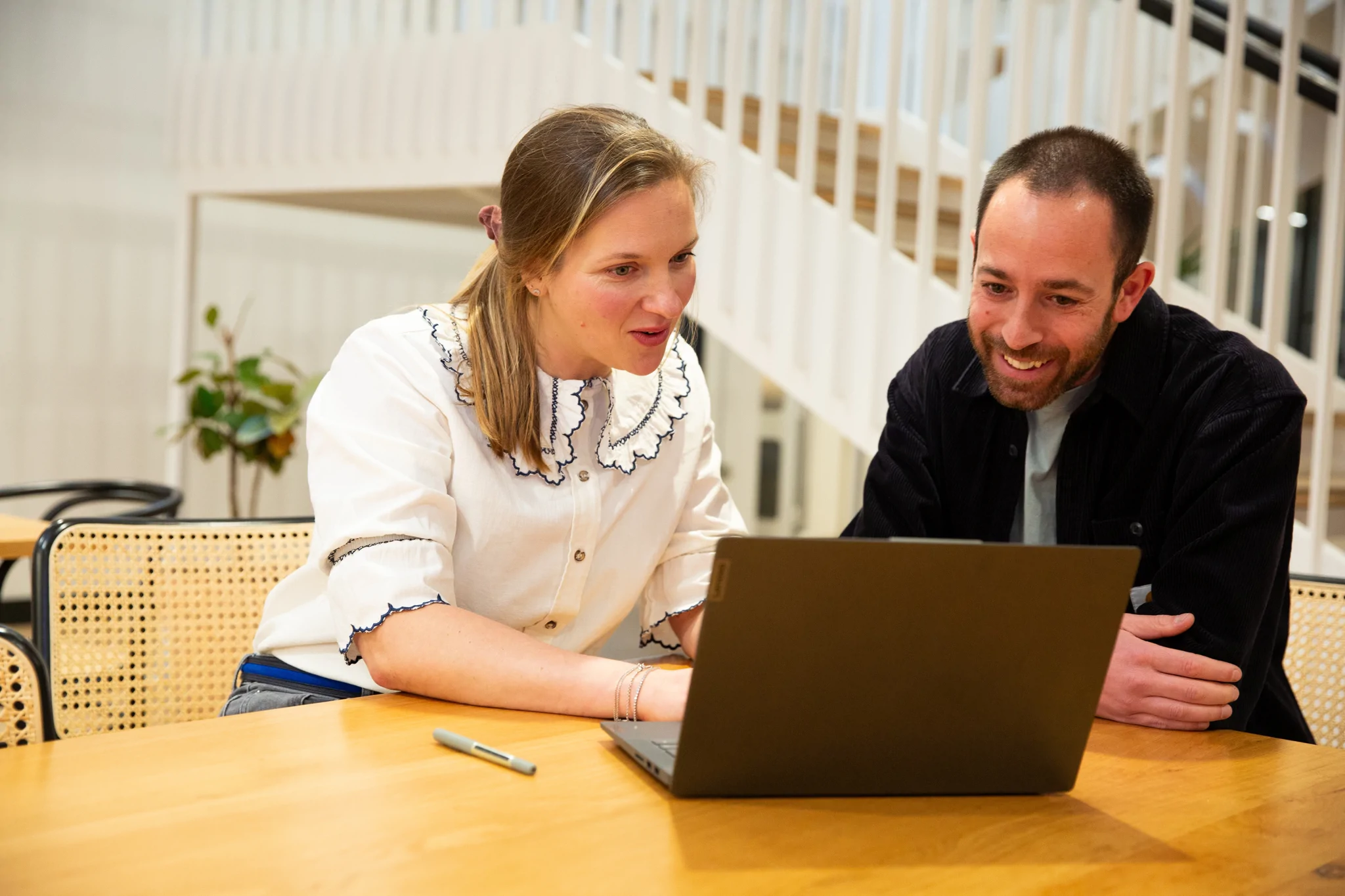 man and woman look at a laptop screen