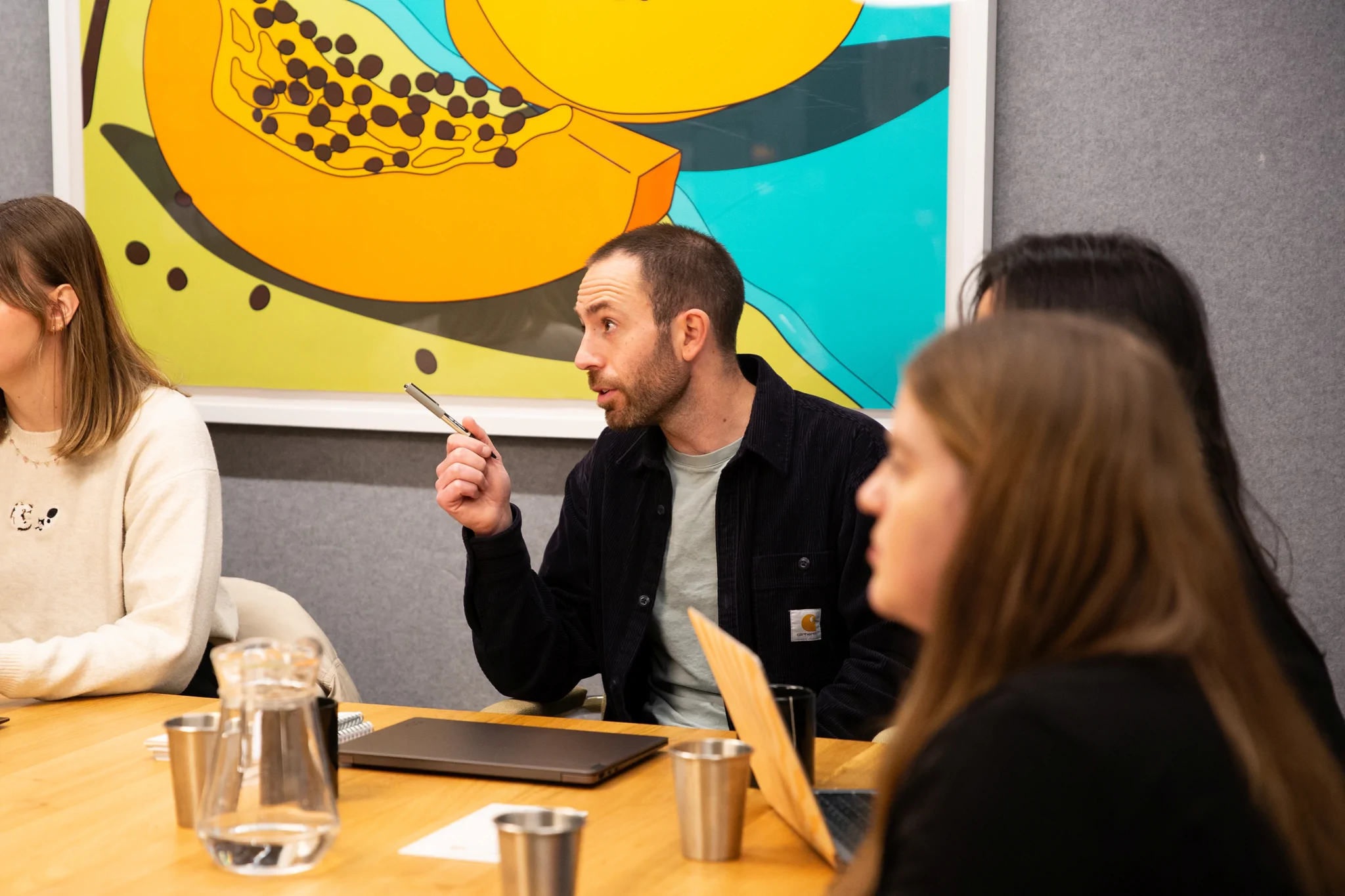 Man using pen to point with colleagues listening