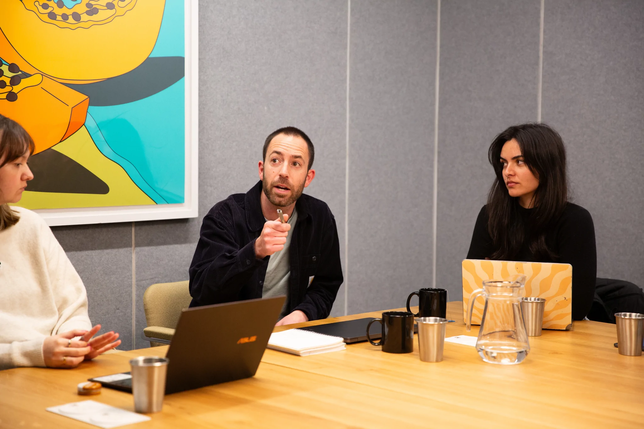 Man explaining point in a board room to two colleagues