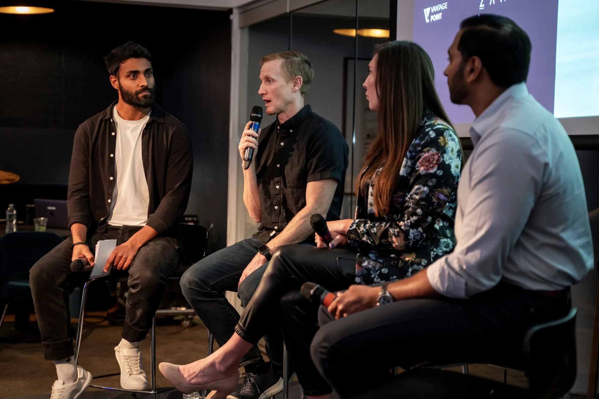 event panel with three guests and one host holding microphones