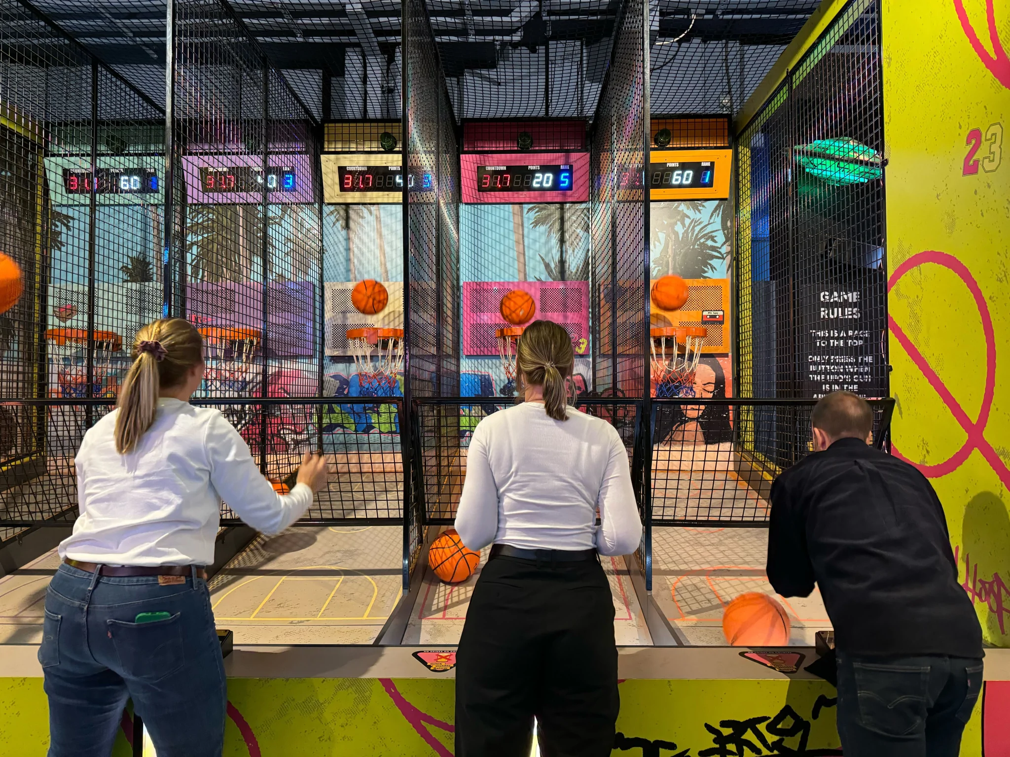 Three people shooting hoops at a carnival